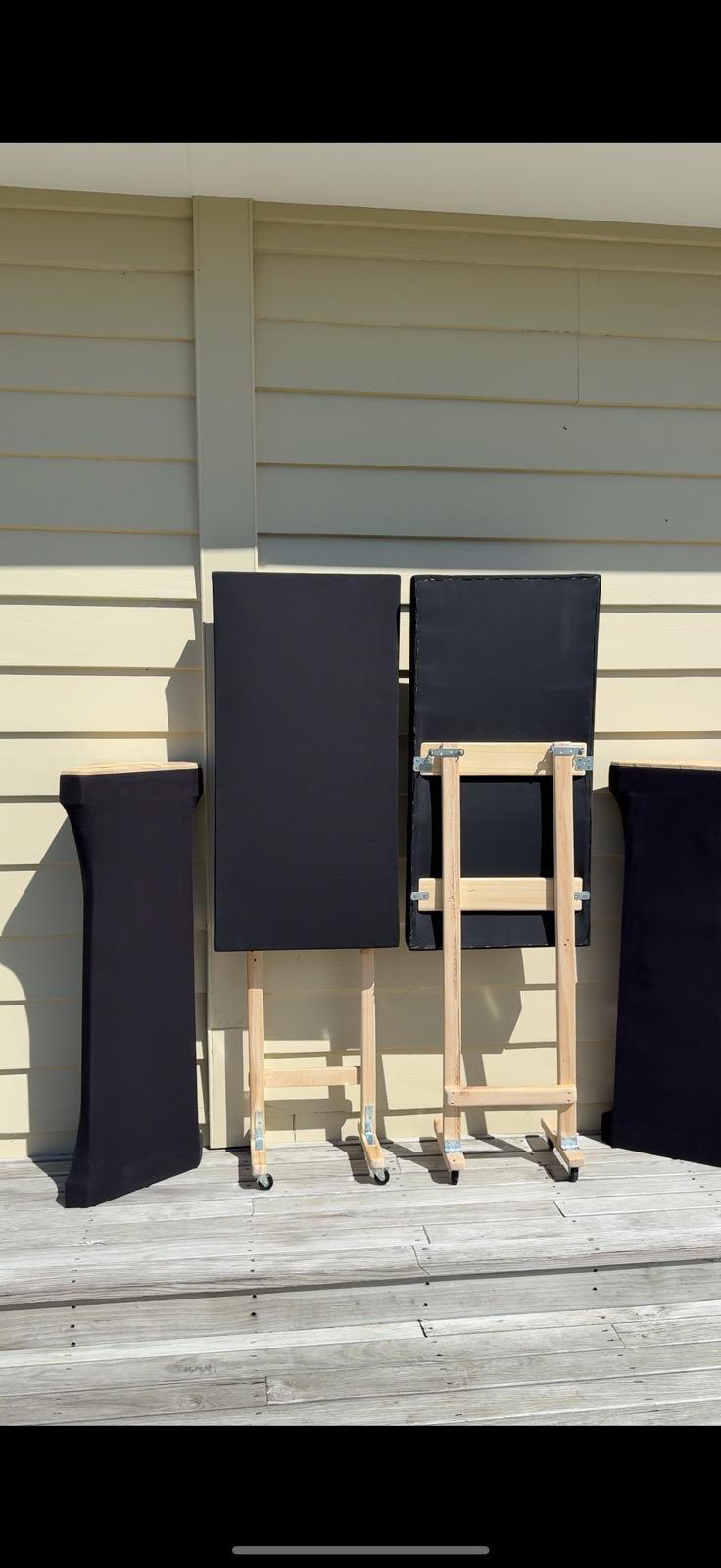 Three finished acoustic panels leaning against an exterior weatherboard wall in the sun